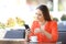 Woman stirring coffee checking smart phone in a bar