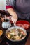 Woman stirring Hot and Boiling Shabu broth with cabbage, eryngii, enotitake, tofu and Kurobuta pork inside hot pot