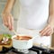 Woman stirring pasta sauce in kitchen