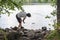 Woman stone skipping or skimming into a lake, remembering and nostalgic for childhood