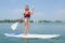 Woman stood on windsurfing board holding oar