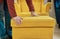 Woman in a store chooses for buy a chair and a footstool made of yellow fabric