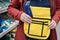Woman in store chooses sturdy yellow tool bag. In bag is blue adjustable wrench