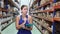 Woman storekeeper keeps track of goods on the shelves of a construction warehouse or store