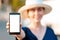 A woman in straw hat holds a smartphone in her hand, hand close-up. Portrait in a blur. Concept of modern technologies, business