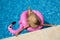 Woman with straw hat in the pool with an inflatable pink flamingo