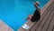 Woman in straw hat relaxing on edge of pool