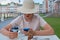 A woman in a straw hat with a smartphone sits in a street cafe and eats her dessert