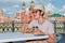 A woman in a straw hat with a smartphone sits in a street cafe and eats her dessert