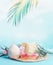 Woman straw hat with sunglasses, palm leaves and coconut drinks on blue sky background with hanging tropical leaves. Holiday beach