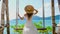 Woman in a straw hat sways gently on a swing overlooking the turquoise sea