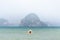Woman in straw hat swiming in the sea in Krabi Railey beach overlooking the harbour and mountains, Thailand