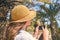 Woman in the straw hat taking selfie picture or video using smartphone in the palm forest. Seychelles islands.