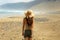 Woman in straw hat walking on a tropical beach who looking like an incredible martian landscape.