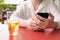 woman at a street cafe table holds a smartphone in her hands