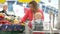 A woman stretches a yellow sweet pepper to her one-year-old son. Mom and baby in the supermarket choose vegetables