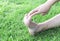 Woman stretching exercises feet finger on green grass background