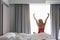 Woman stretching near bed after waking up with sunrise at morning, back view