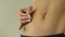 Woman stretching skin on anorexic torso, no fat layer, insecurities, closeup