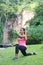 Woman stretching tricep back of arm while doing lunge in an outdoor park.