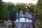 Woman in a striped dress carries a bunch of colorful balloons across a decorative bridge. Fountain in Pyatigorsk, Russia