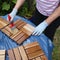 A woman strokes wood preservation glaze on square wood panels to make them weatherproof.