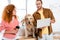 Woman stroking cute golden retriever and businessman holding laptop in office