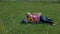 Woman stroking her stomach while resting on the blanket with sunflowers bouquet