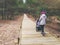 Woman with stroller walking on wooden pedestrian path in forest