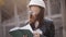 The woman student architect on a construction site examines the technical documentation and makes notes in his notebook