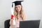 Woman student with diploma behind a laptop. Online education, exam, graduation concept