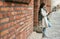 Woman, student and tablet leaning on brick wall writing, design or doing research in the city. Female university learner