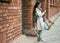 Woman, student and tablet relaxing on brick wall writing, design or doing research in the city. Female university