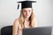 Woman student takes an online exam, defends a diploma behind a laptop. Online education, graduation concept