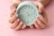 Woman with stylish color nails holding alarm clock on pink background, closeup