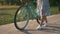 Woman in stylish outfit is walking with vintage retro bike in park in sunshine. Charming girl with bicycle in park at sunset. Bike