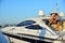 Woman in stylish swimsuit and captain hat on private speed-boat on vacation