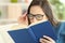 Woman suffering eyestrain reading a book with eyeglasses