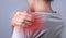 Woman suffering from shoulder pain. Hand holding painful shoulder with red point closeup. Joint injuries. Health care