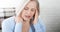 Woman suffering from stress or a headache grimacing in pain as she holds the back of her neck with her other hand to her