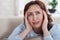 Woman suffering from stress or a headache grimacing in pain as s