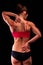 Woman suffers from pain in her back and neck after workout, black background