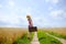 Woman with suitcase jumping on road between field