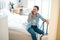 Woman with a suitcase sitting on bed in hotel room and using phone