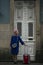 A woman with a suitcase stands at the front door of a traditional building in Porto, Portugal.