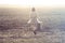 Woman with suitcase walking toward infinity in a desert place