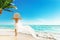 Woman Summer Beach Vacation. Travel Girl Sunbathing in Sun Hat, Bikini, White fluttering Dress. Women Back View looking at Ocean