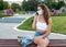 Woman in summer in city calls on smartphone, protective medical mask on her face, quarantine and lockdown in summer in