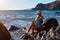 Woman sunbathing sitting on rock. Beautiful lady in blue dress. Nature, spa time and meditation concept. Copy space