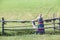 Woman in sundress standing near village fence in field